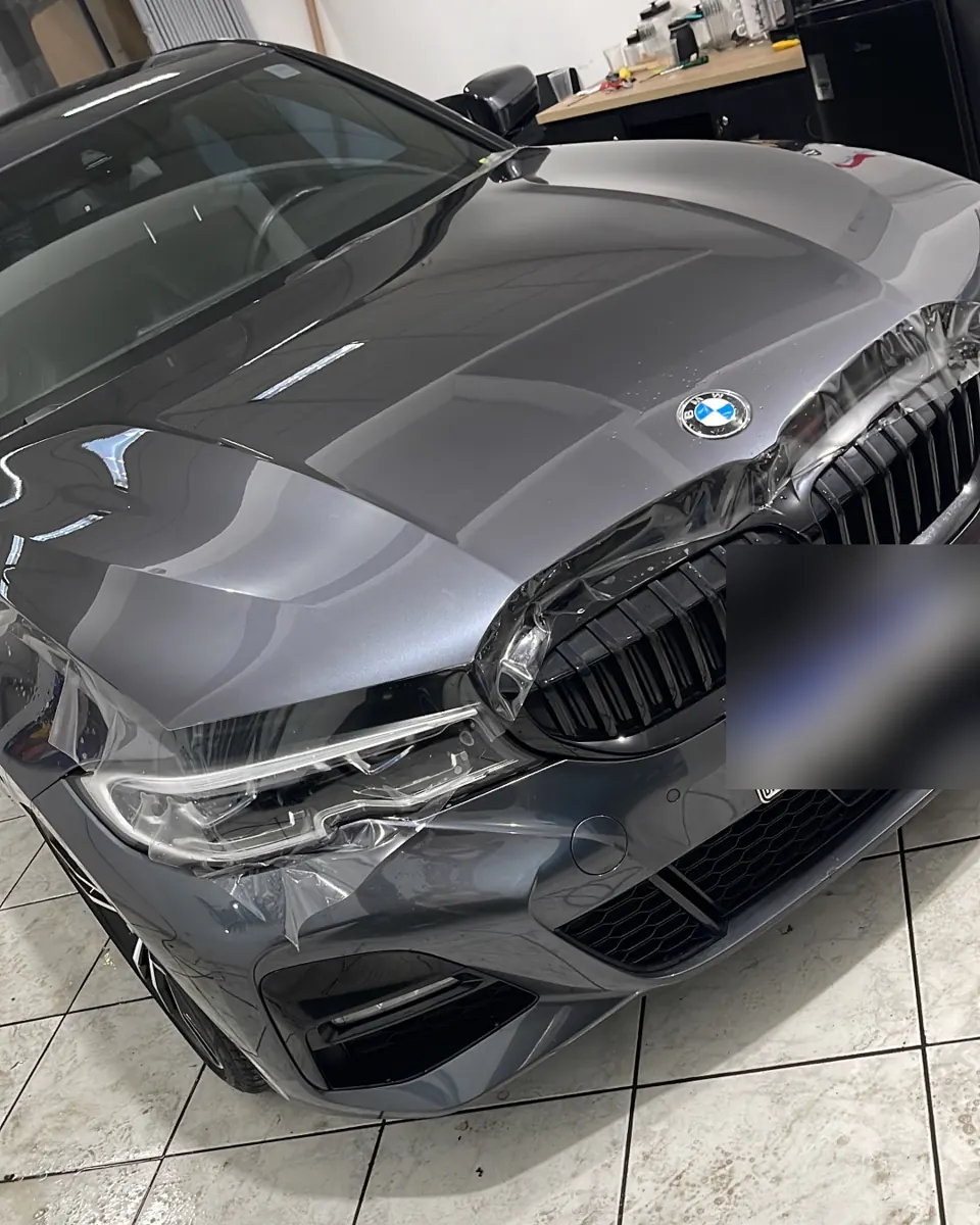 BMW cinza com PPF sendo aplicado no capô e para-choque